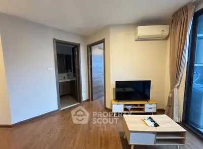 Modern living room with wooden flooring, TV setup, and air conditioning in a cozy apartment.