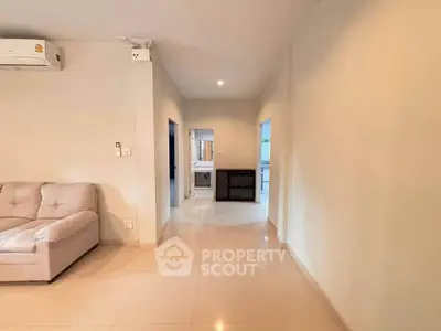 Spacious living area with modern sofa and sleek tile flooring in a bright apartment.