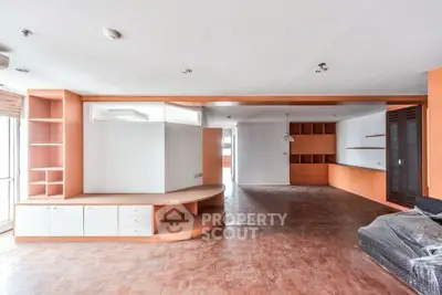 Spacious open-plan living room with built-in wooden shelves and natural light