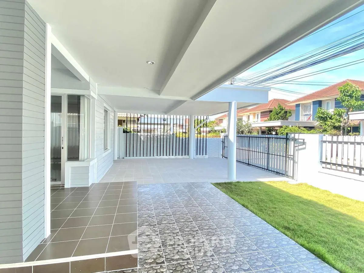 Spacious modern patio with tiled flooring and lush green lawn in suburban home.