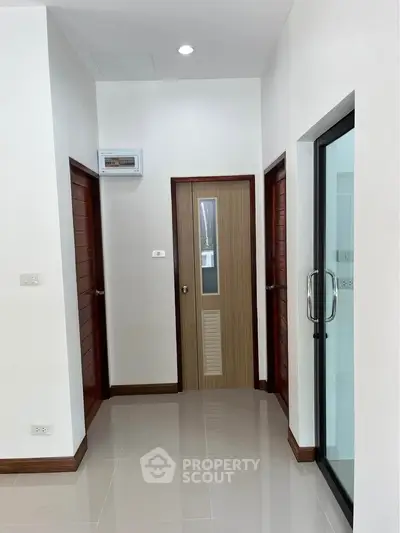 Modern hallway with sleek doors and glossy tiled flooring in a contemporary home.