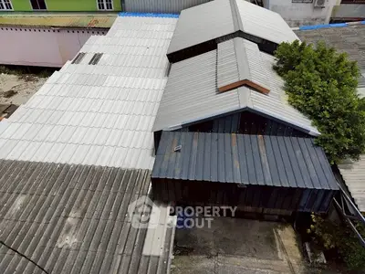Aerial view of industrial buildings with metal roofs and surrounding area.