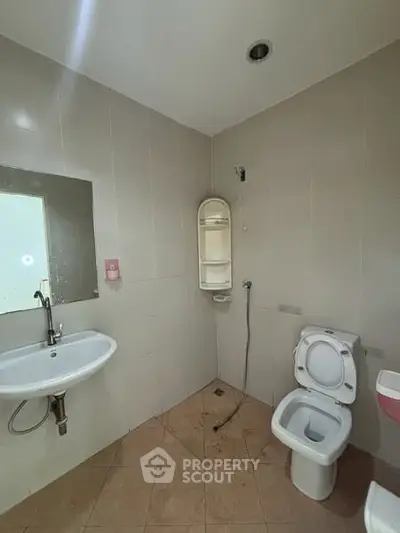 Modern bathroom with wall-mounted sink and toilet, featuring a sleek design and neutral tiles.