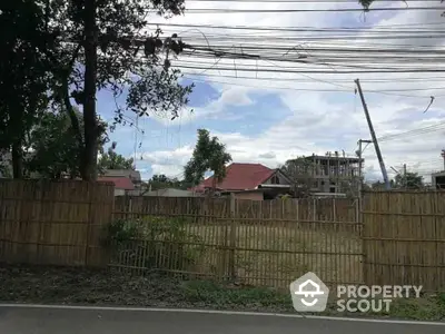 Vacant land with bamboo fencing and surrounding residential area under a clear sky.