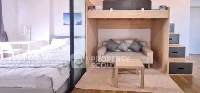 Modern studio apartment with loft bed and cozy living area, featuring stylish furniture and natural light.
