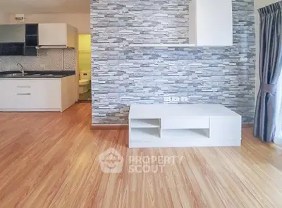 Modern open-plan living room with stylish stone accent wall and sleek kitchen area.