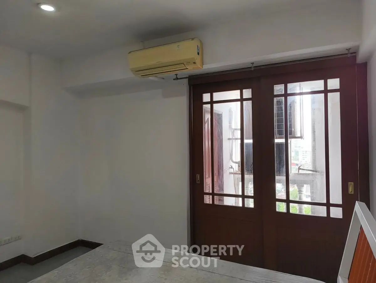 Spacious room with air conditioning and sliding glass doors leading to balcony with city view.