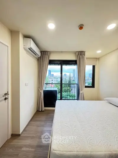 Modern bedroom with city view, featuring large window, air conditioning, and elegant decor.