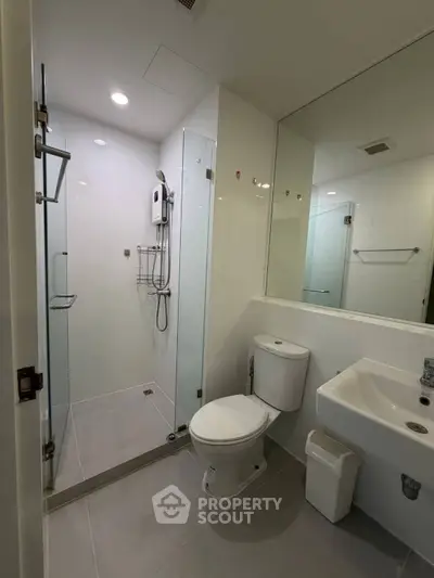 Modern bathroom with glass shower and sleek fixtures in contemporary apartment.