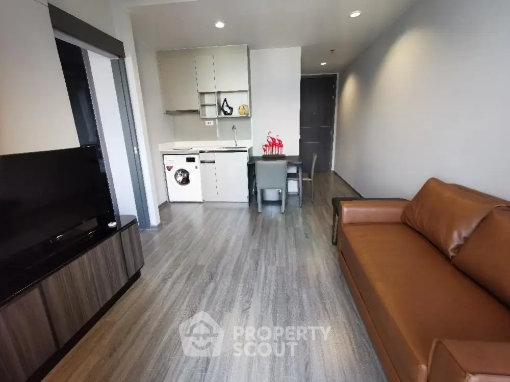 Modern living room with open kitchen, featuring sleek furniture and stylish decor.