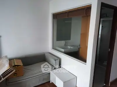 Cozy interior space with a small sofa and a view into a modern bathroom.