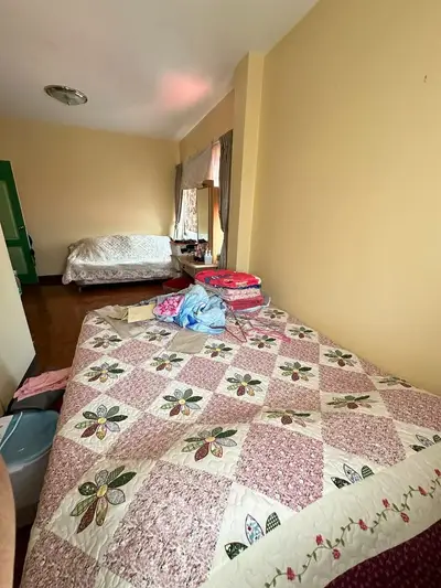 Cozy bedroom with floral quilt and natural light, perfect for relaxation.