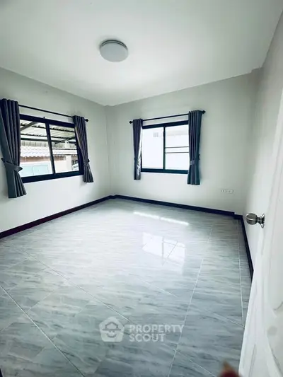 Spacious empty room with large windows and tiled flooring, ready for customization.