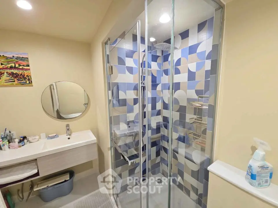 Modern bathroom with stylish geometric shower tiles and sleek vanity unit.