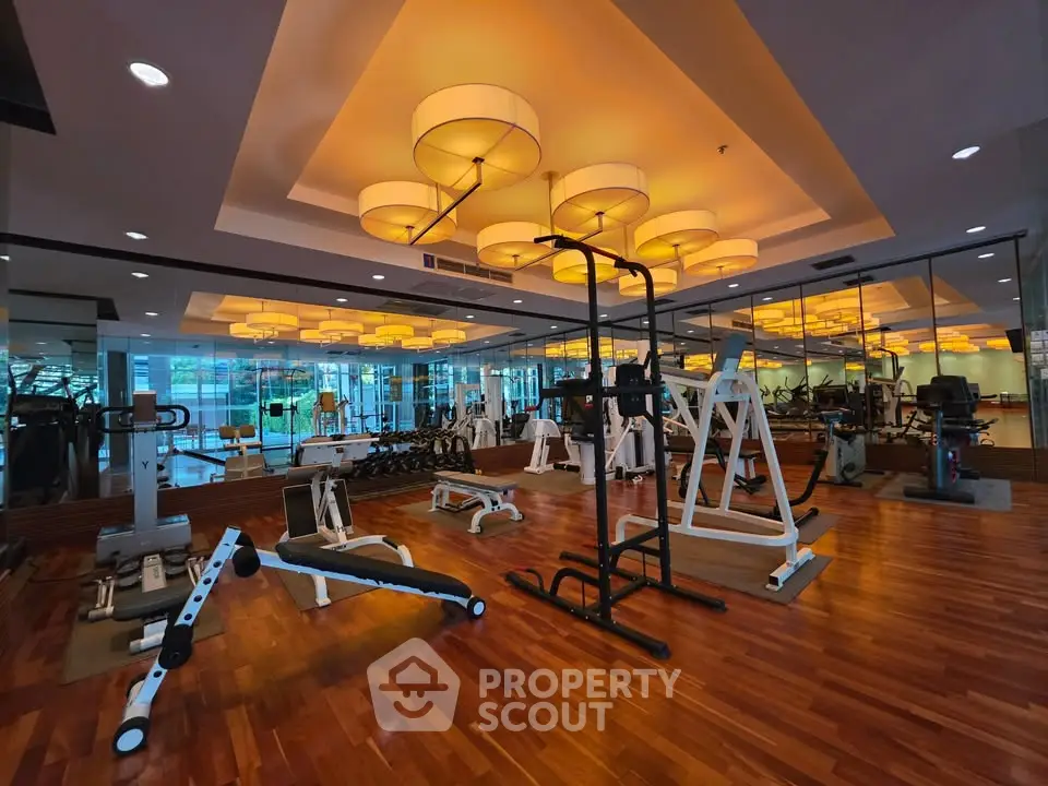 Luxurious gym with modern equipment and stylish lighting in upscale residential building.