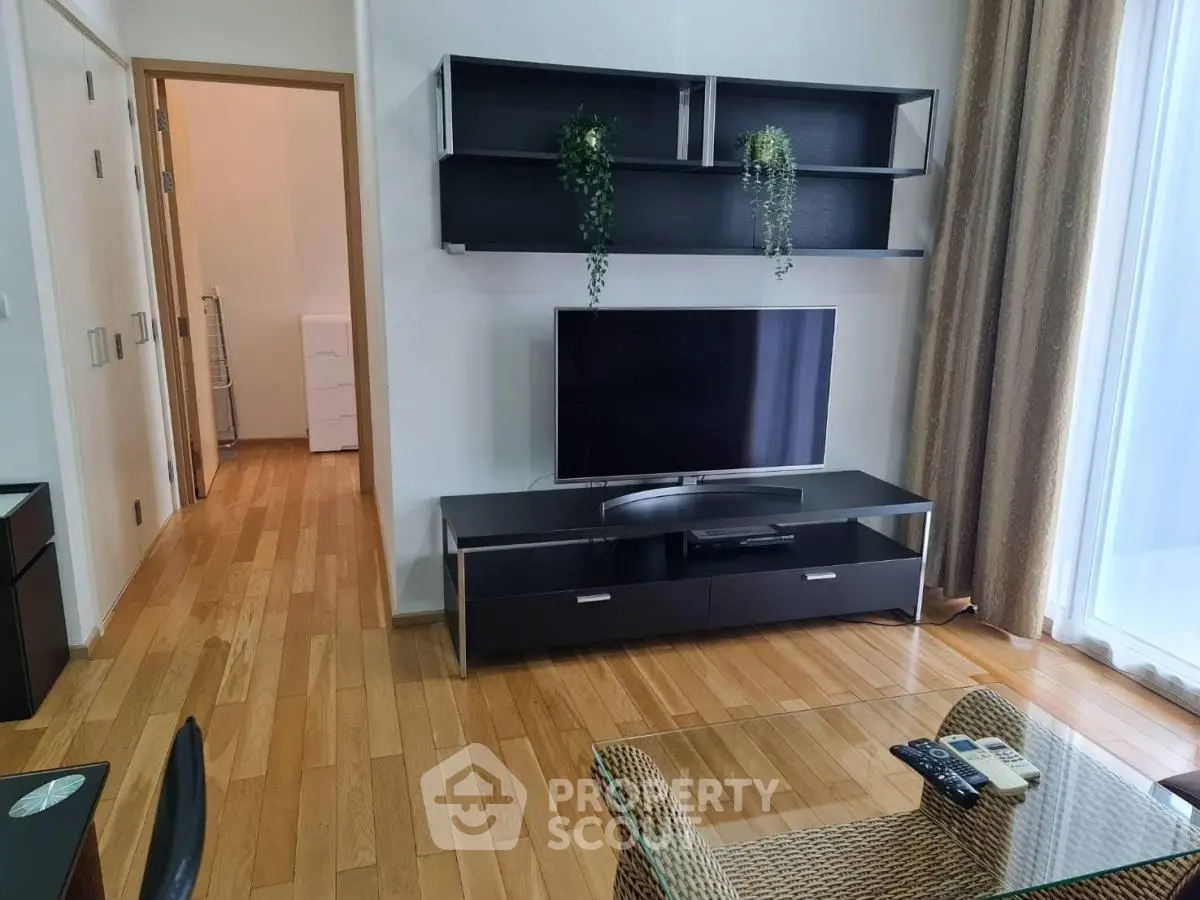 Modern living room with sleek TV stand and wall shelves, wooden flooring, and natural light.