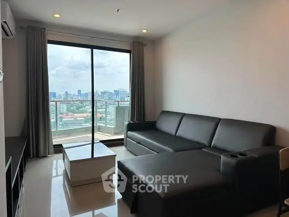 Modern living room with city view and sleek black sofa in high-rise apartment.