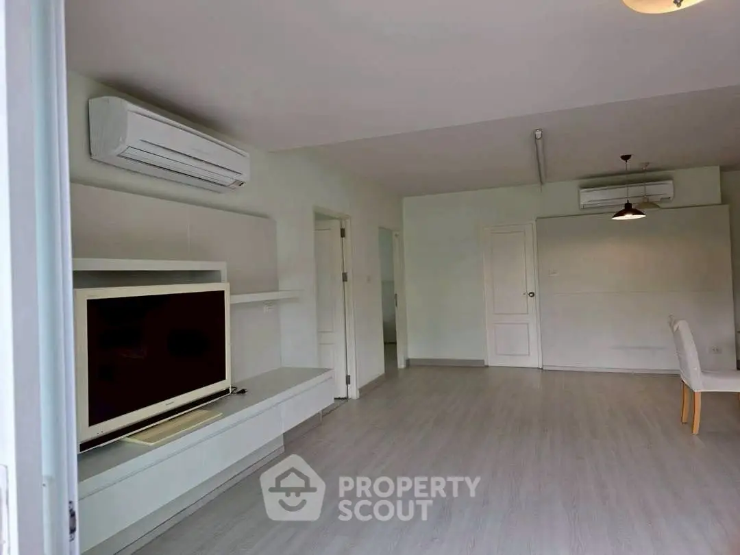 Spacious living room with modern air conditioning and sleek flooring, perfect for comfortable living.