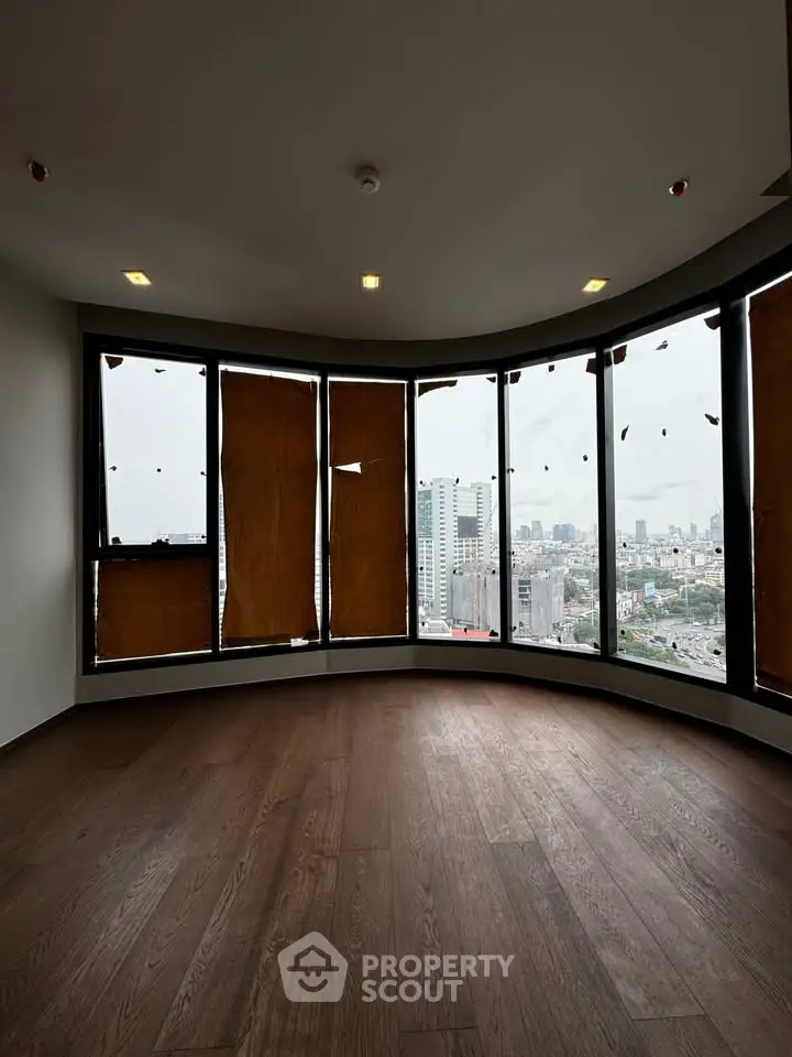 Spacious curved window room with city view and wooden flooring