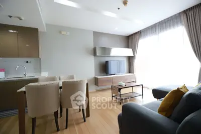 Modern living room with open kitchen, stylish furniture, and natural light.