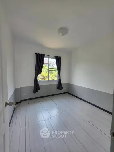 Bright empty bedroom with large window and modern tile flooring