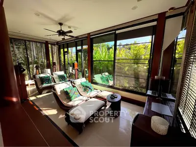 Luxurious sunlit living room with tropical garden view and elegant furnishings.