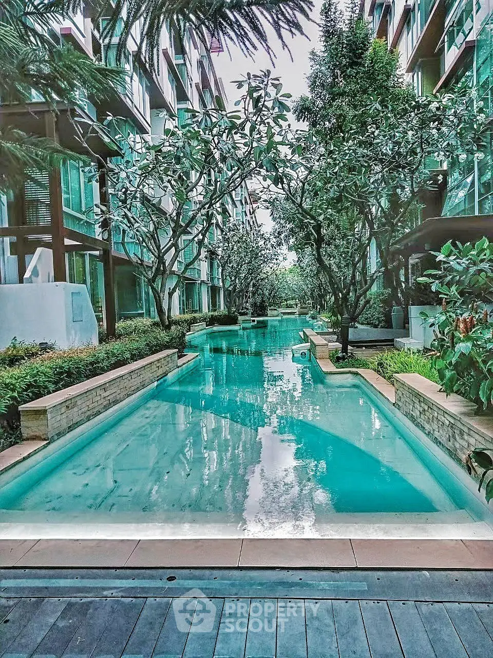 Luxurious residential pool surrounded by lush greenery and modern architecture, offering a serene oasis in the city.