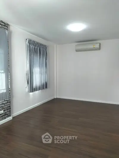 Spacious empty room with wooden flooring and air conditioning, perfect for customization.