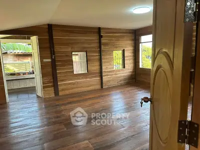 Charming wooden interior room with large windows and polished floors, perfect for cozy living.