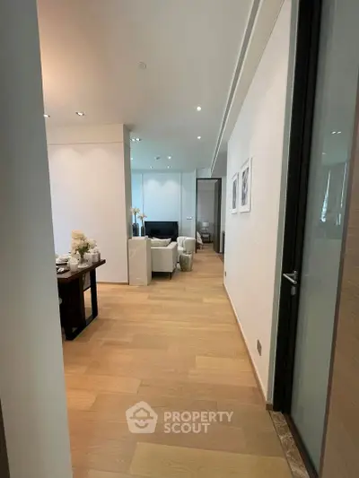 Modern apartment hallway leading to a stylish living room with wooden flooring and elegant decor.