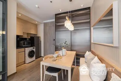 Modern kitchen with integrated appliances and a cozy dining area, featuring sleek cabinetry and a warm, inviting ambiance.