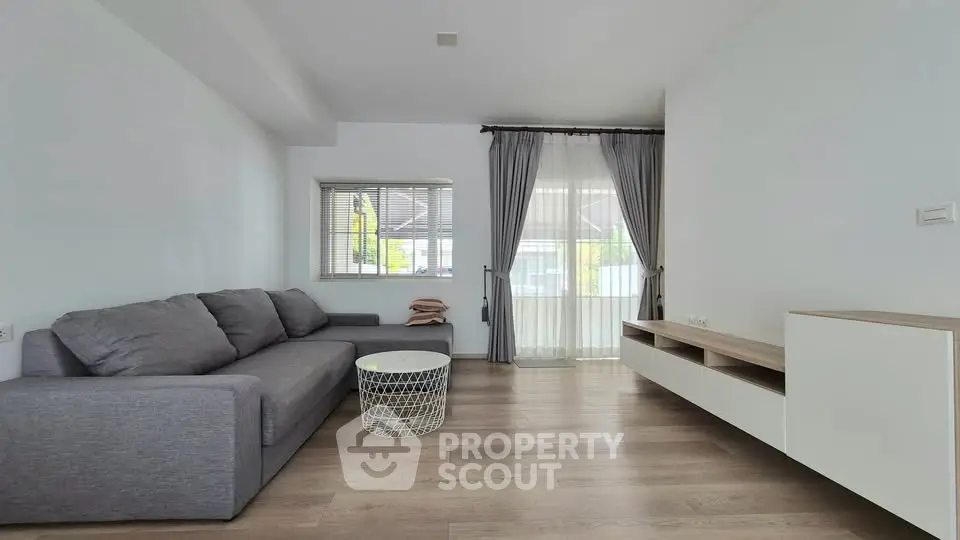 Modern living room with gray sofa, stylish coffee table, and large window with curtains.