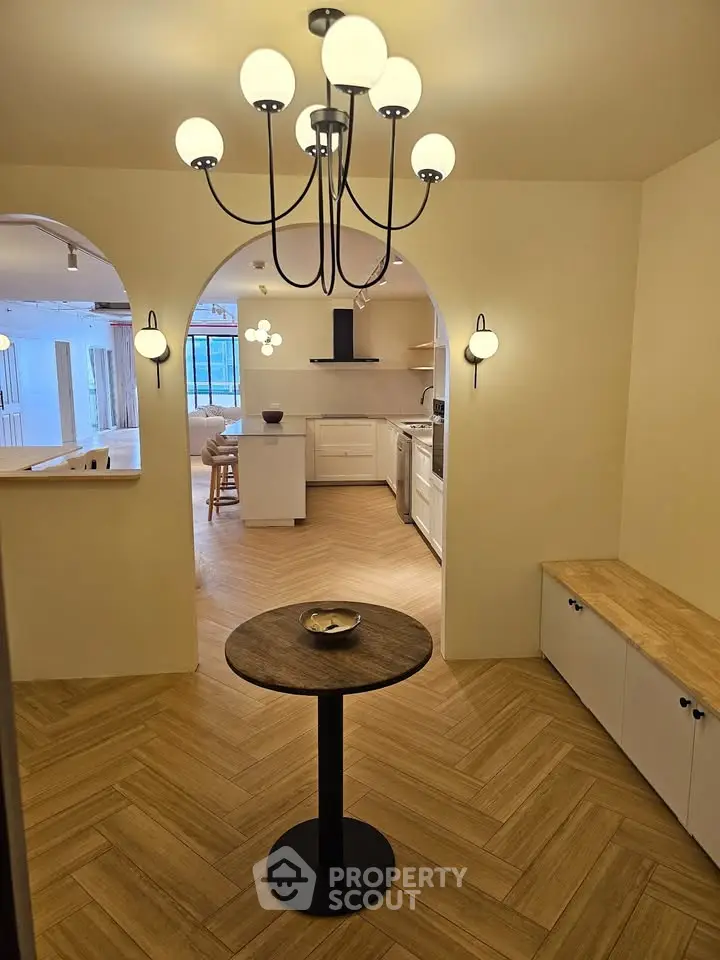 Elegant open-layout kitchen with modern lighting and wooden flooring, perfect for stylish living.