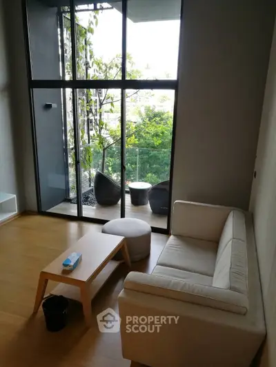 Serene living room with floor-to-ceiling windows offering a lush garden view, complemented by modern minimalist furniture.