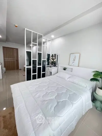 Modern bedroom with stylish decor and partition, featuring a cozy bed and sleek flooring.