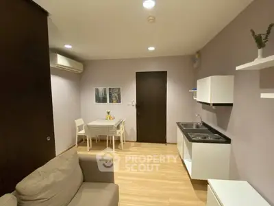 Modern living room with compact kitchen and dining area, featuring sleek design and cozy ambiance.