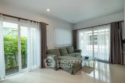 Bright living room with large windows and cozy green sofa, perfect for relaxation.
