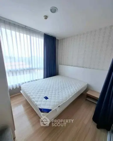 Spacious bedroom with large window and modern decor in a real estate property.