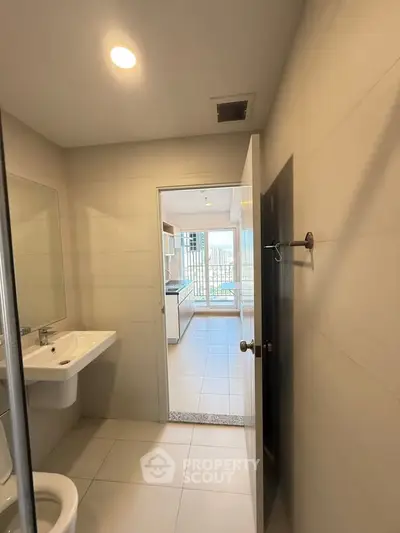 Modern bathroom with sleek design leading to a bright kitchen area.