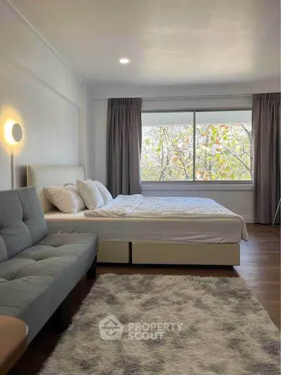 Spacious bedroom with large window and cozy seating area