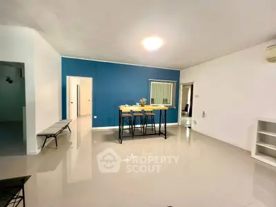 Spacious modern living room with stylish blue accent wall and sleek dining area.