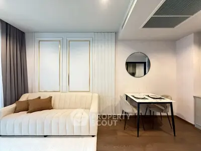 Modern living room with elegant sofa and dining area, featuring stylish decor and warm lighting.