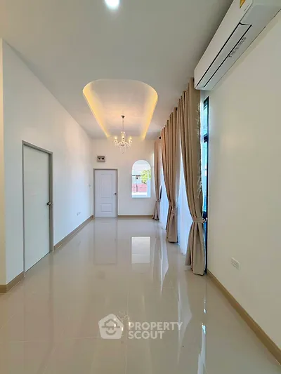 Elegant living room with high ceiling and chandelier, featuring large windows and modern air conditioning.