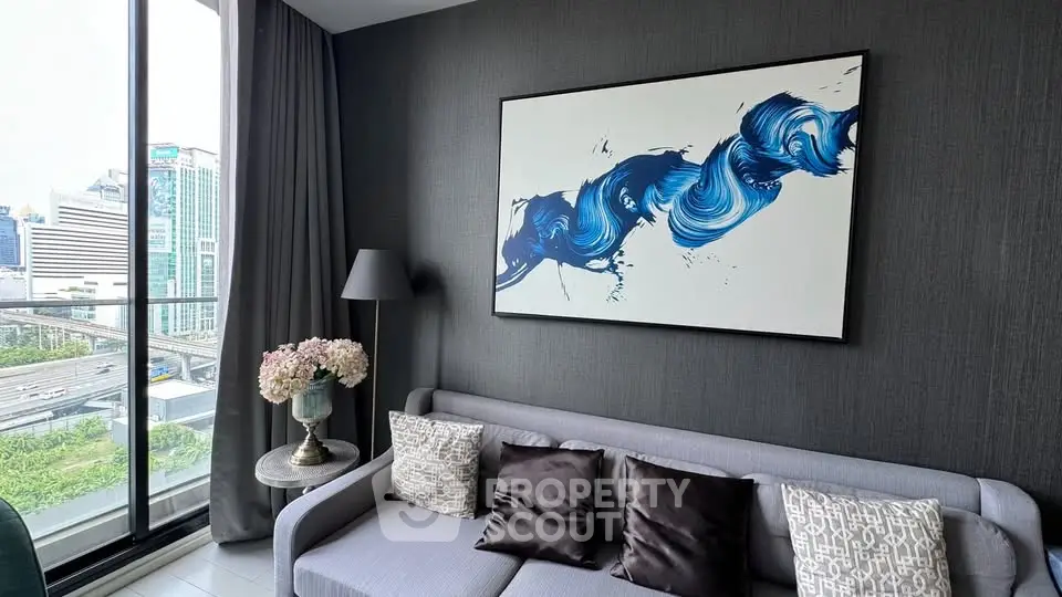 Modern living room with stylish decor and city view, featuring a large window and contemporary artwork.