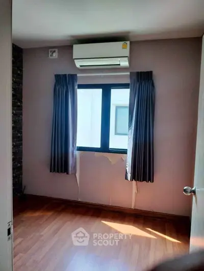 Cozy room with air conditioning and wooden flooring, perfect for a small study or bedroom.