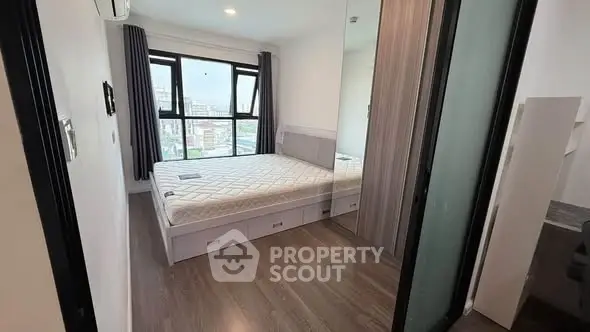 Modern bedroom with large window and mirrored wardrobe in urban apartment