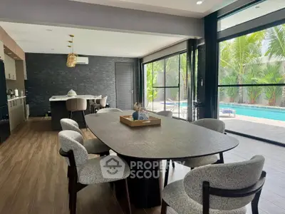 Luxurious open-plan dining area with pool view, modern kitchen, and elegant decor in a tropical setting.