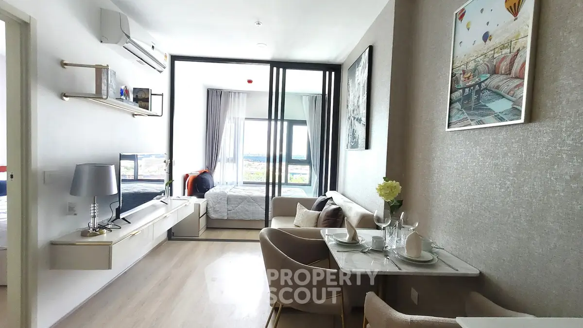 Modern open-plan living room with dining area and bedroom view, featuring stylish decor and natural light.