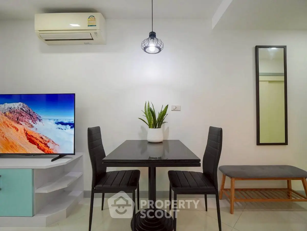 Modern dining area with sleek table, chairs, and wall-mounted TV in stylish apartment.