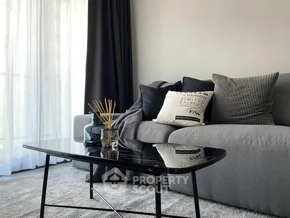 Modern living room with sleek black coffee table and cozy gray sofa.